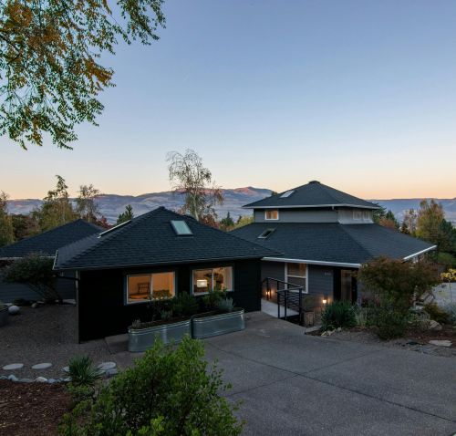 Elegant suburban house with spacious driveway and stunning mountain views at sunset.